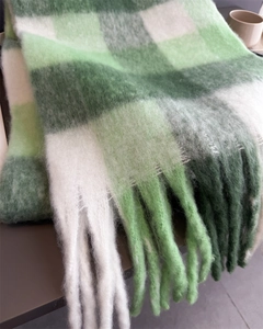 Gros plan d'une écharpe en mohair à carreaux verts avec franges épaisses et texture douce