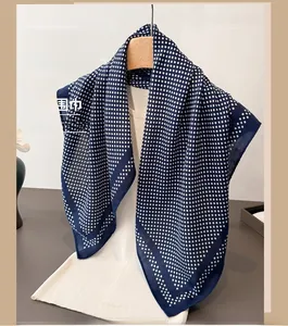 Detail of navy blue silk square scarf with white polka dots draped on a hanger