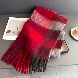 Détail de la texture d'une écharpe en tricot à carreaux avec franges sur un coffret cadeau