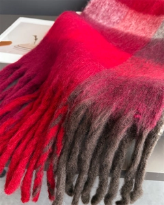 Gros plan sur une écharpe épaisse à carreaux avec franges rouges et texture laineuse