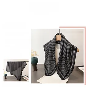 Detailed view of lightweight black polka dot scarf with elegant solid border on hanger