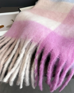 Gros plan d'une écharpe en mohair à carreaux rose et blanc avec de longs glands tressés
