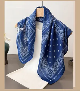 Detail of royal blue paisley scarf with white patterns on a minimal wooden hanger