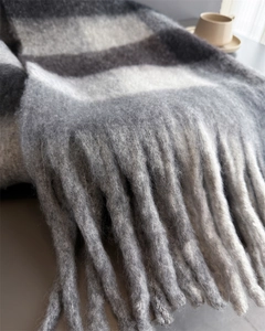 Détail d'une écharpe à carreaux montrant les franges et la texture douce en mohair