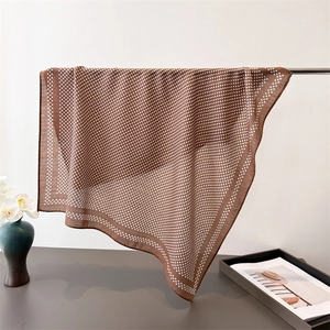Detail of elegant brown polka dot silk scarf draped on a metal bar in a luxury setting