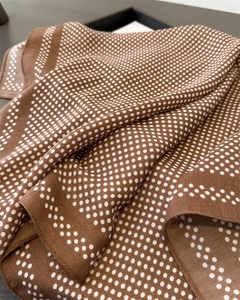 Close-up of brown silk scarf featuring white polka dots and elegant flowing texture