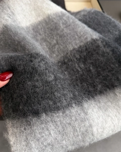 Gros plan sur une écharpe à carreaux gris avec texture mohair douce et détails frangés