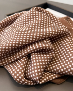 Close-up of brown silk scarf with white polka dots showing soft texture and premium fabric drape