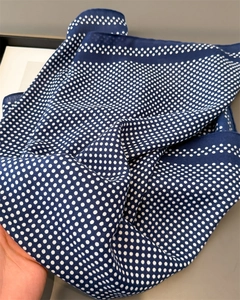 Detail of soft navy blue silk scarf with white polka dot pattern and fine stitched edges