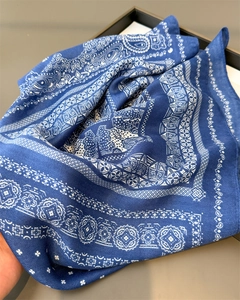 Detail of dark blue paisley scarf with geometric patterns on a soft fabric texture