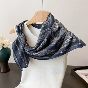 Detail of navy blue paisley silk scarf styled on a white tank top with floral decor