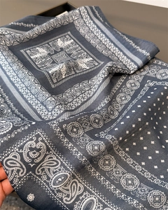 Detailed view of dark paisley silk-touch scarf with white geometric patterns
