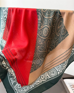 Detailed close-up of a paisley pattern scarf with rich red, brown and green colors