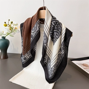 Elegant herringbone patterned silk-like scarf with paisley print on a wooden hanger