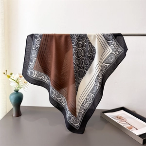 Detail of lightweight paisley pattern scarf with brown color block and fringed edge texture