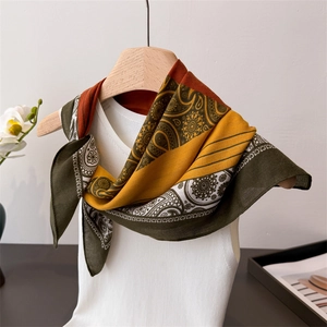 Elegant paisley patterned silk scarf in deep green and orange on a minimalist background