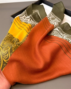 Detail of herringbone linen-feel scarf featuring orange paisley patterns and thick texture