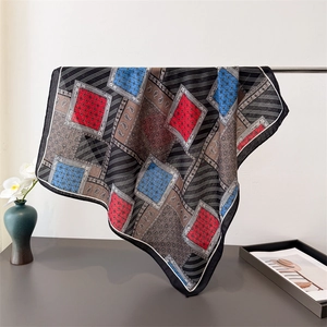 Black paisley silk-like square scarf with red and blue geometric patterns hanging on rack