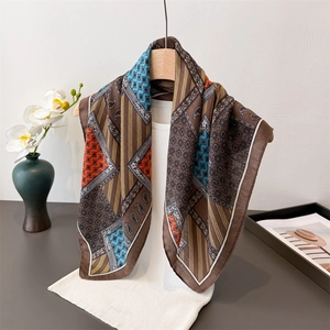 Bohemian paisley printed silk scarf in brown and blue draped on a wooden hanger