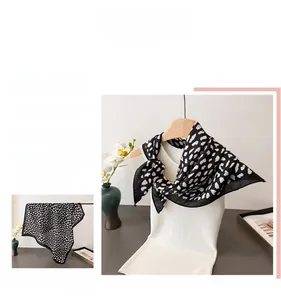 Detail of elegant black and white heart pattern silk scarf tied on a white hanger