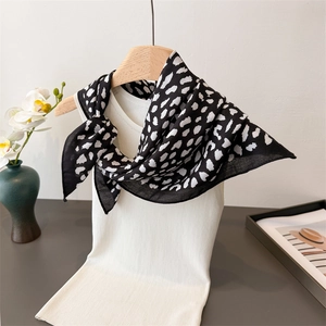 Detail of leopard print scarf on a white knit top with elegant home decor background