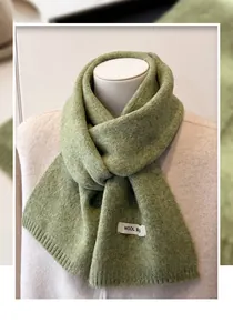 Detail of wool knit scarf in grass green with visible white WOOL fabric label