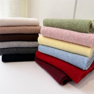 Detailed stack of soft knitted scarves in 12 colors showing plush cashmere-like texture