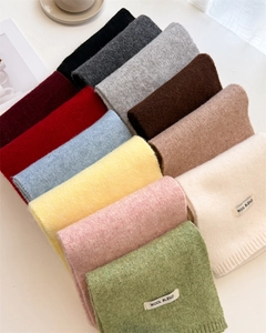 Detailed flat lay of wool blend scarves in various colors showing texture and labels
