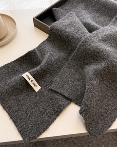 Macro shot of dark grey wool blend knitted scarf texture with wool blend brand tag