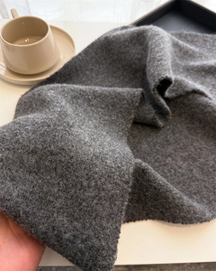 Close-up of thick dark grey knitted scarf showing soft texture and premium warm fabric