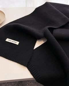 Detail of black wool blend knit scarf featuring premium ribbed edges and soft texture