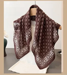 Détail de motifs géométriques et bordure ethnique sur foulard marron aspect lin