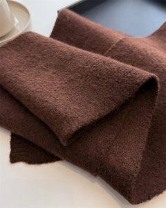 Close-up of deep brown knitted scarf showing soft texture and ribbed edge details