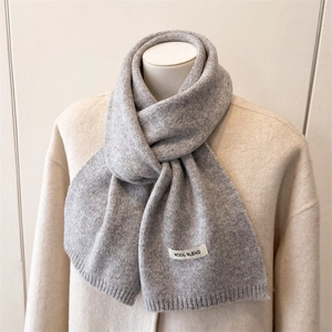 Detail of light gray wool blend scarf with ribbed texture and woven material label