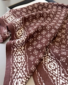 Gros plan détaillé du foulard marron foncé avec motifs géométriques blancs et texture douce