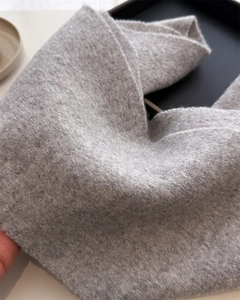 Detailed macro view of the grey wool-like textured fabric with warm curly grain finish