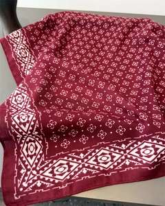 Détail d'un foulard bordeaux avec motif géométrique blanc et texture aspect lin