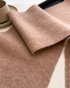 Close-up of soft knitted scarf texture with premium cashmere blend drape in camel pink