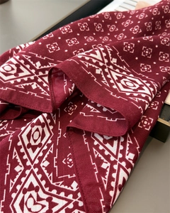 Détail macro du foulard rouge vin avec motifs géométriques blancs et texture de tissage