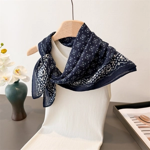 Détail d'un foulard bleu marine à motifs géométriques sur un débardeur blanc