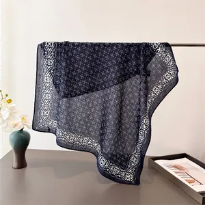 Détail d'un foulard bleu marine à motif géométrique avec texture drapée et ourlet fin