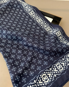Détail macro montrant le tissage sergé et les motifs géométriques sur le foulard en soie bleu