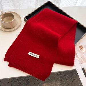 Detail of red wool blend scarf showing the wash label and fine ribbed knit texture