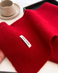 Detailed close-up of a red wool blend knit scarf with a white rectangular texture label