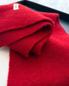 Detail view of red knitted wool blend scarf showing texture and WOOL BLEND label