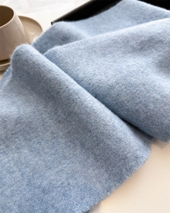 Close-up of light blue knitted scarf texture showing soft and fuzzy premium wool fibers