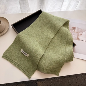 Close-up of grass green wool blend scarf showing ribbed knit texture and label