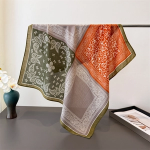 Elegant olive and orange paisley square scarf draped on a metal stand for display