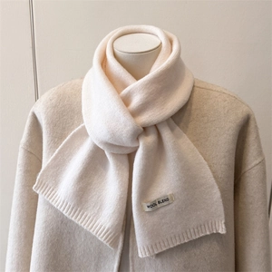 Close-up of cream wool blend knitted scarf showing thick ribbed texture and soft fabric