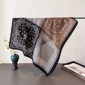 Detail of paisley pattern silk scarf draped on metal rack with floral background decor